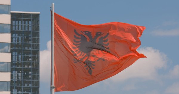 Albanian and European Union flags flying together against a blue sky