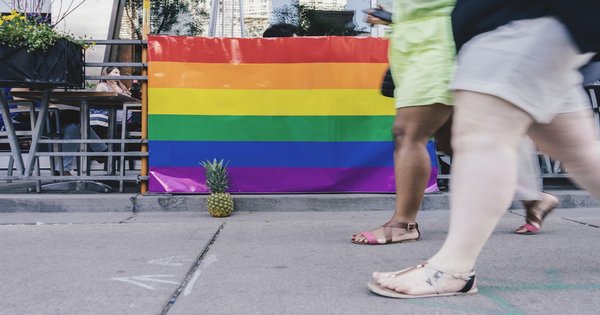 Rainbow pride flag held against a backdrop of Balkan mountains