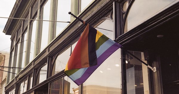 A person holding a rainbow flag on a city street in Southeast Europe