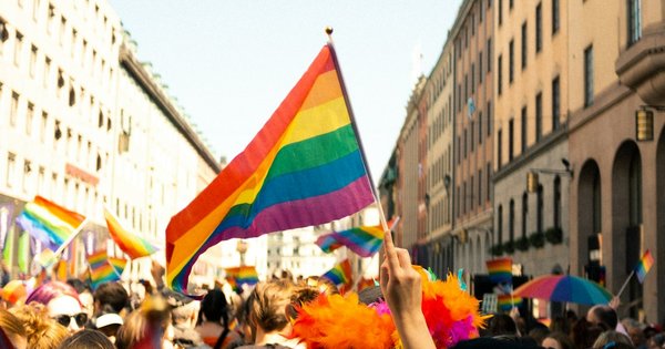 Rainbow flags raised against a Balkan city skyline during a Pride march
