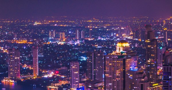 Bangkok skyline at sunset with rainbow lights illuminating a city street