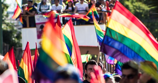 Crowd of Pride marchers waving rainbow flags on a city street in Eastern Europe