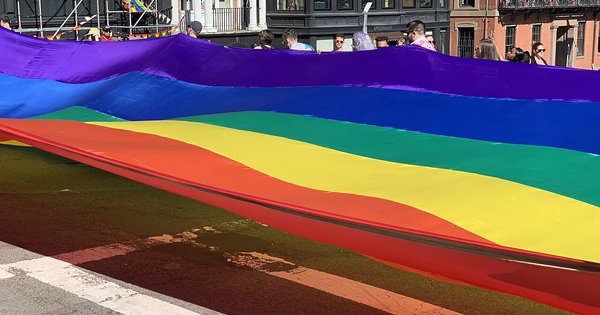 A Pride flag held up at a march in a European city square