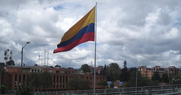 A Pride flag flies over a street in a Colombian city