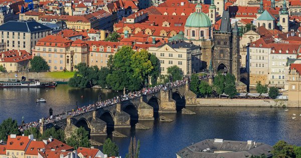 View of Prague's Charles Bridge and Old Town rooftops at sunset