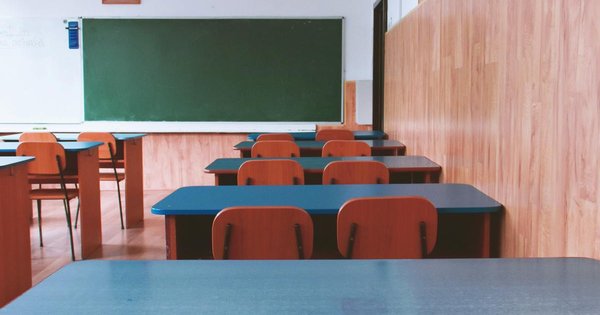 An empty American public school classroom with desks and a chalkboard