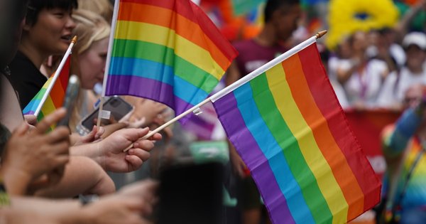 Marchers carrying rainbow flags fill a European city street during a Pride parade