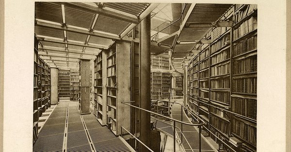 Long rows of bookshelves stretching into the distance in a library reading room