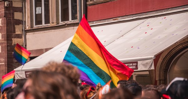 A rainbow flag flying in front of French architecture in Paris