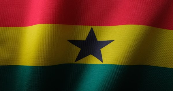 Ghanaian flag waving against a cloudy sky above Accra