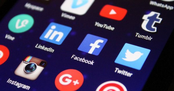 A smartphone showing social media app icons against a rainbow background