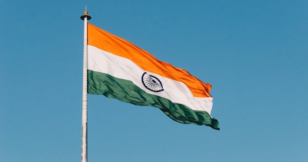 The Indian national flag waving against a clear blue sky
