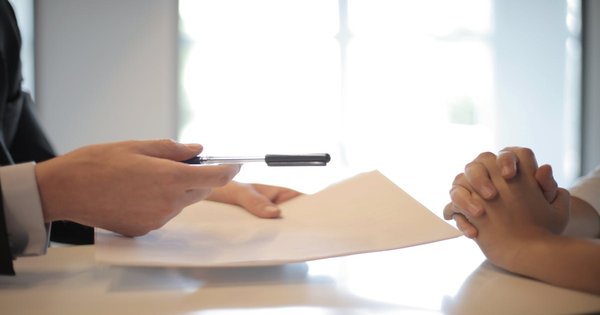 A person presenting official documents across a desk