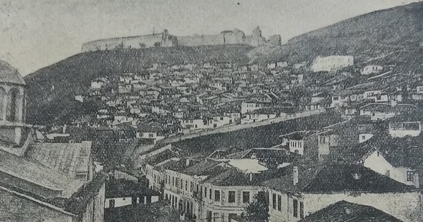 The historic old town of Prizren, Kosovo, with a stone bridge over the river and a mosque minaret against the hills