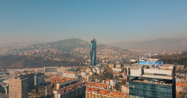 Rooftops and minarets of Sarajevo's old town with green hills rising behind