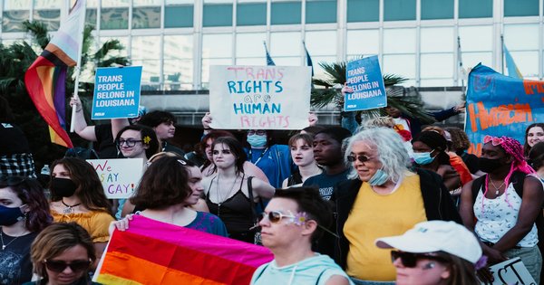 A large crowd marching with pride flags and signs at a trans rights demonstration