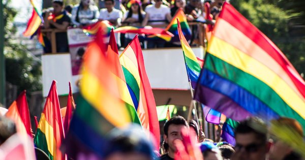 Crowds packing a Madrid boulevard during the MADO Pride parade under rainbow flags