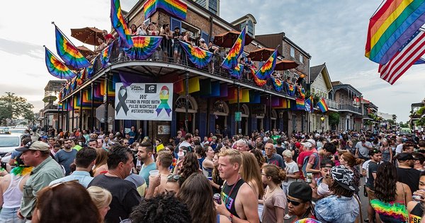 A crowd at a Pride march carrying rainbow flags and banners