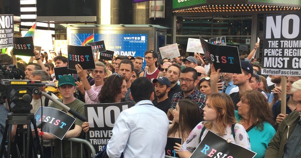 Protesters holding transgender pride flags and signs at a rally against the U.S. military's transgender service ban