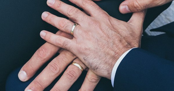 Two wedding rings beside a Polish flag and an EU flag on a wooden surface
