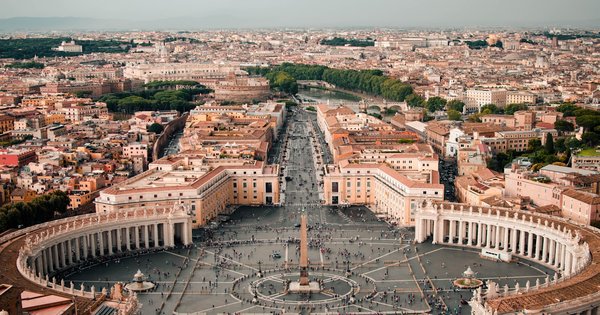 Saint Peter's Square in Vatican City under a clear sky with the basilica dome in the background