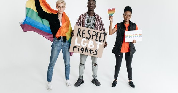 Three demonstrators hold a rainbow flag and signs reading Respect LGBT Rights and Pride