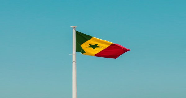 The flag of Senegal waving against a clear blue sky