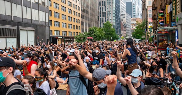 A large crowd of protesters in a European city street during daytime
