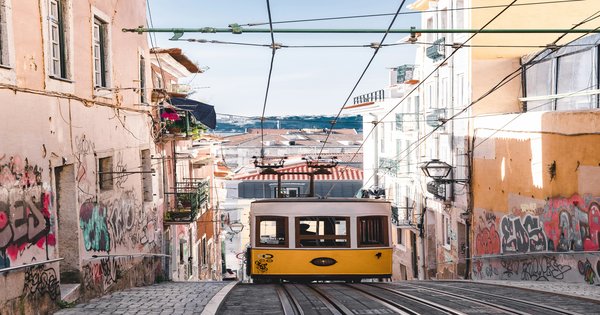 The historic yellow tram climbing a hillside street in Lisbon, Portugal