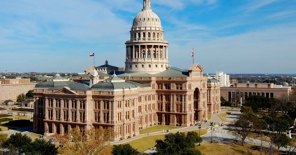 The Texas State Capitol building viewed from the south lawn, with a blue sky