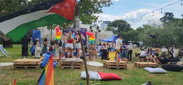 The festival grounds after the march — pallets, rainbow flags, string lights, people relaxing