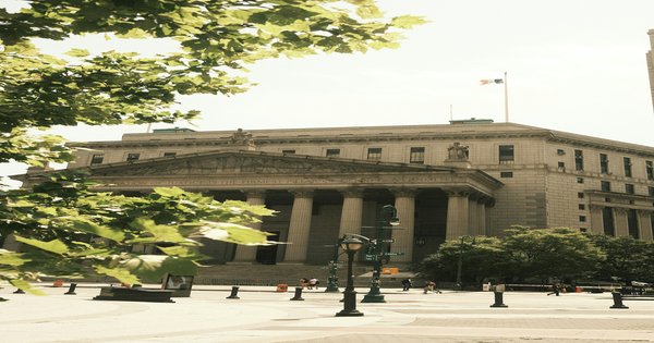 The marble facade and columns of a United States federal courthouse photographed from below against a clear sky