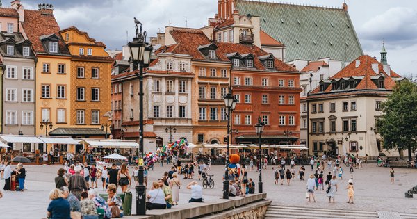 Rainbow flags held aloft by a large crowd marching through central Warsaw