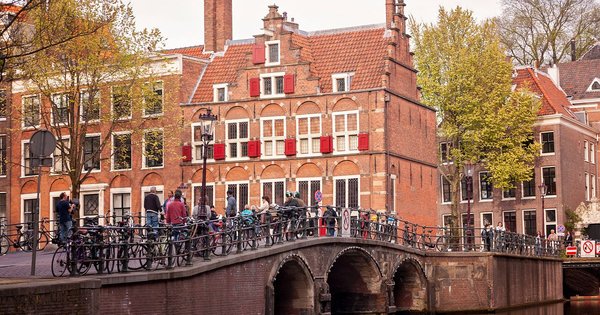 Rainbow flags flying along an Amsterdam canal ahead of WorldPride 2026.