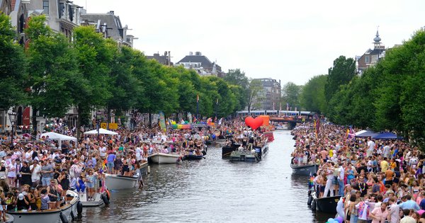Rainbow flags and boats along an Amsterdam canal during Pride