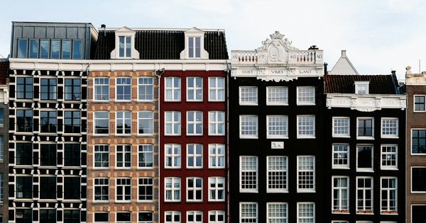 Colorful canal houses reflected in an Amsterdam waterway under a bright sky