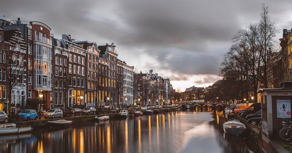 Rainbow flags and boats along an Amsterdam canal during Pride